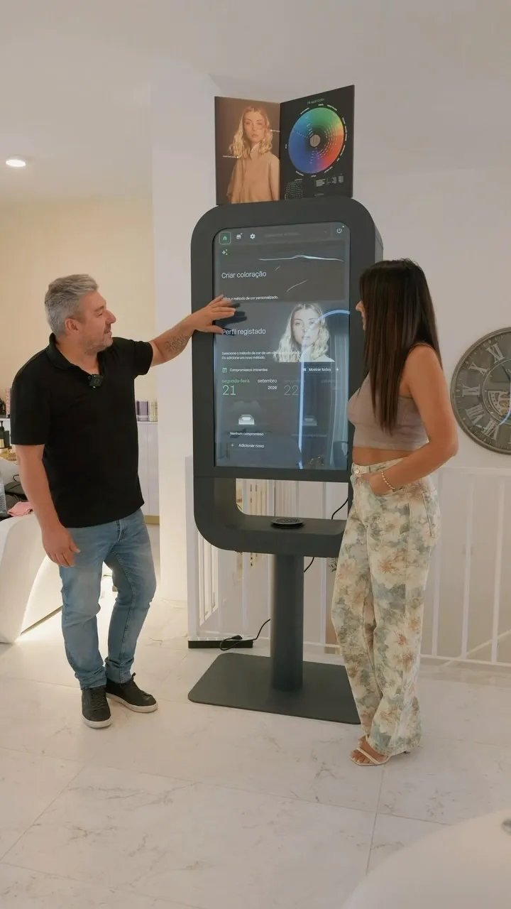 Cabeleireiro e cliente junto a um ecrã de diagnóstico de cor no salão