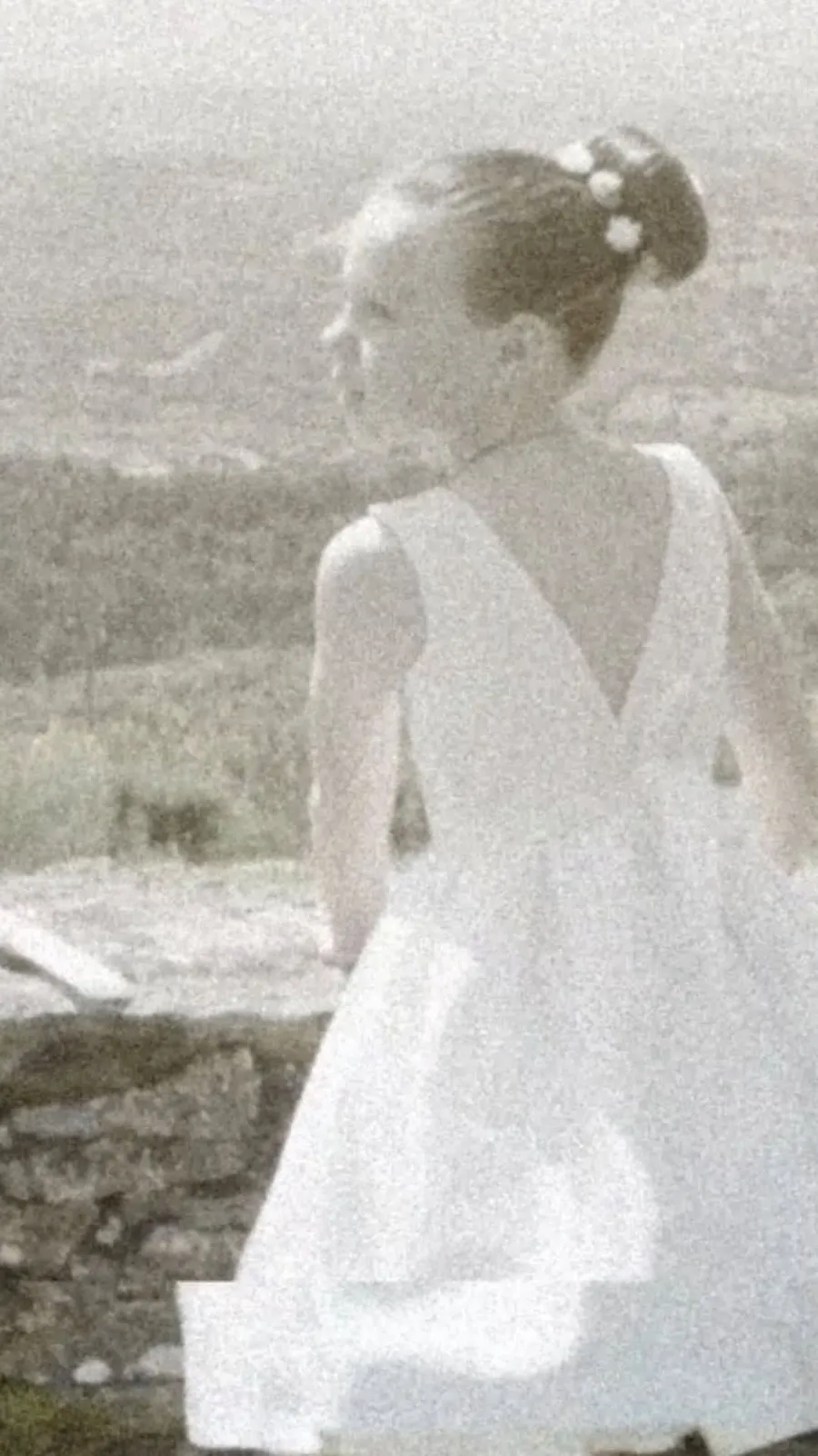 Menina de vestido branco, de costas, com a paisagem ao fundo